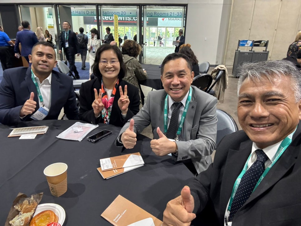 Sohyun Park and international colleagues giving thumbs-up at a business networking event