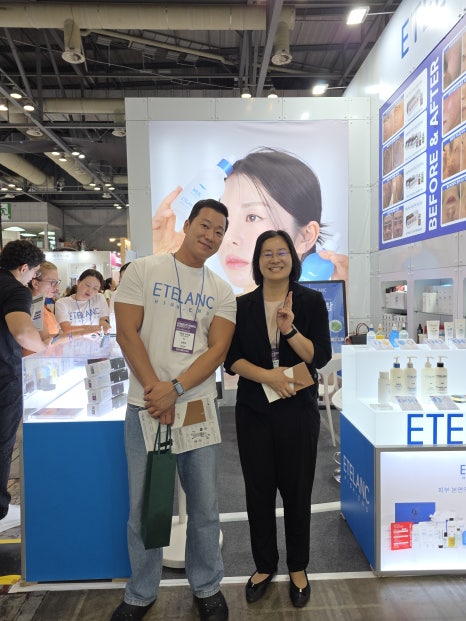 Attorney Sohyun Park posing with a partner at a K-beauty cosmetics booth during a trade expo